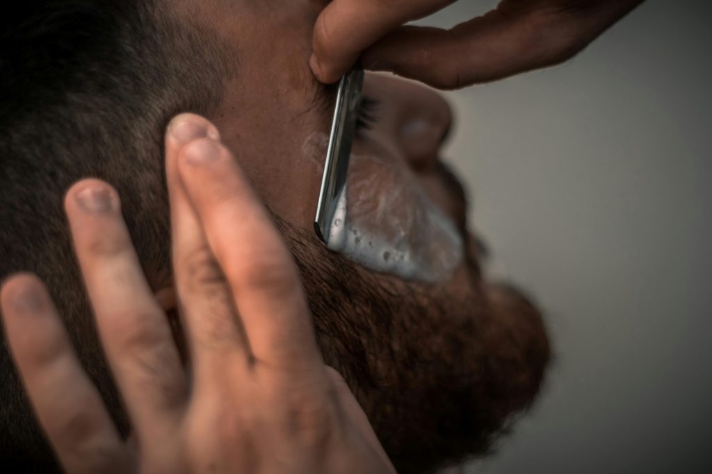 Barber trimming a beard as part of Essential Tips for Maintaining Your Hair and Beard.
